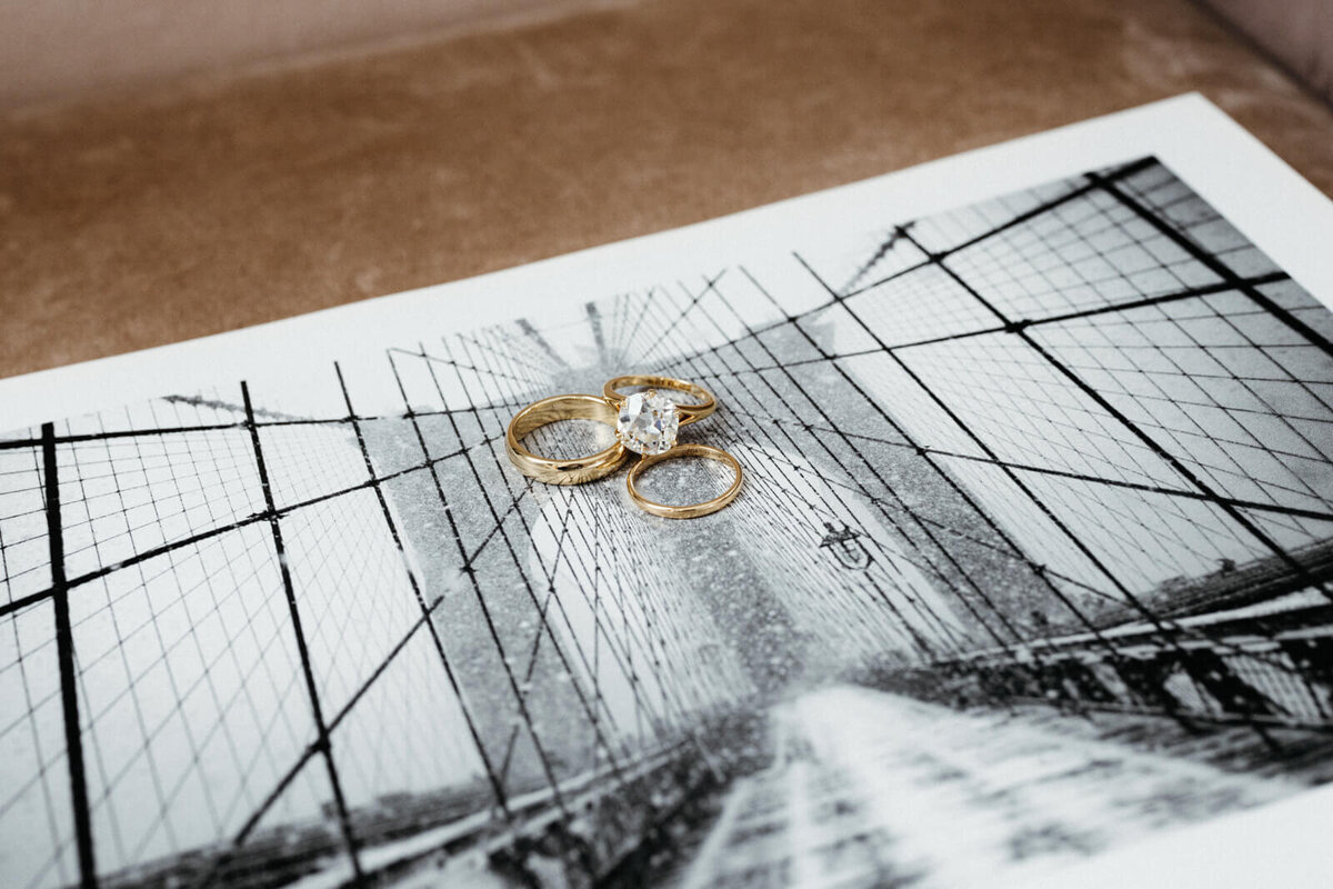 The three gold rings, one of which has a diamond in the center, are placed on top of a black and white photograph.