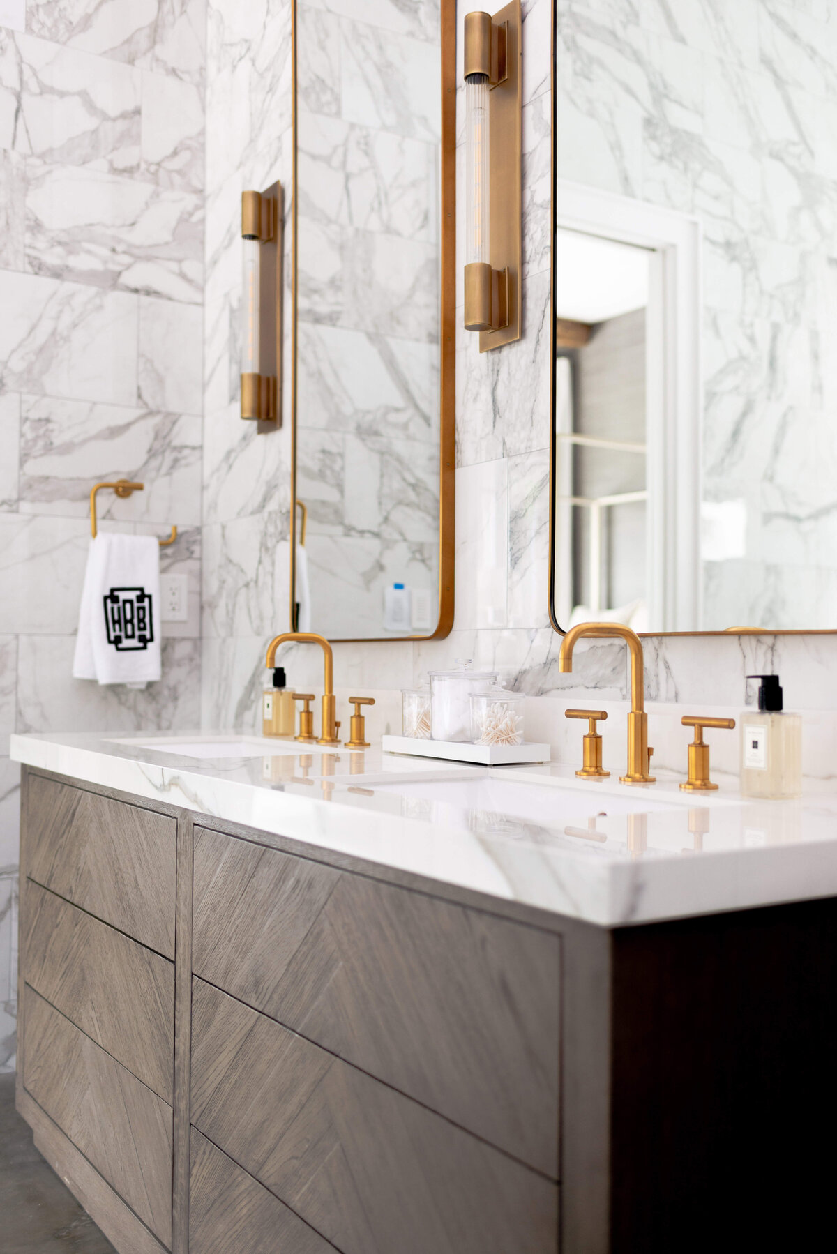 oyster creek studios building belt new build dark wooden vanity with gold hardware and marble walls in bathroom