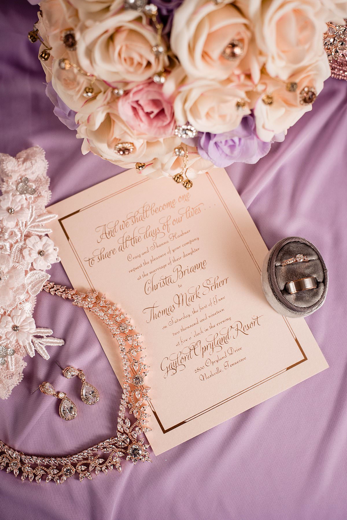 Wedding invitation with ivory, pink and purple roses and brides rose gold jewelry around