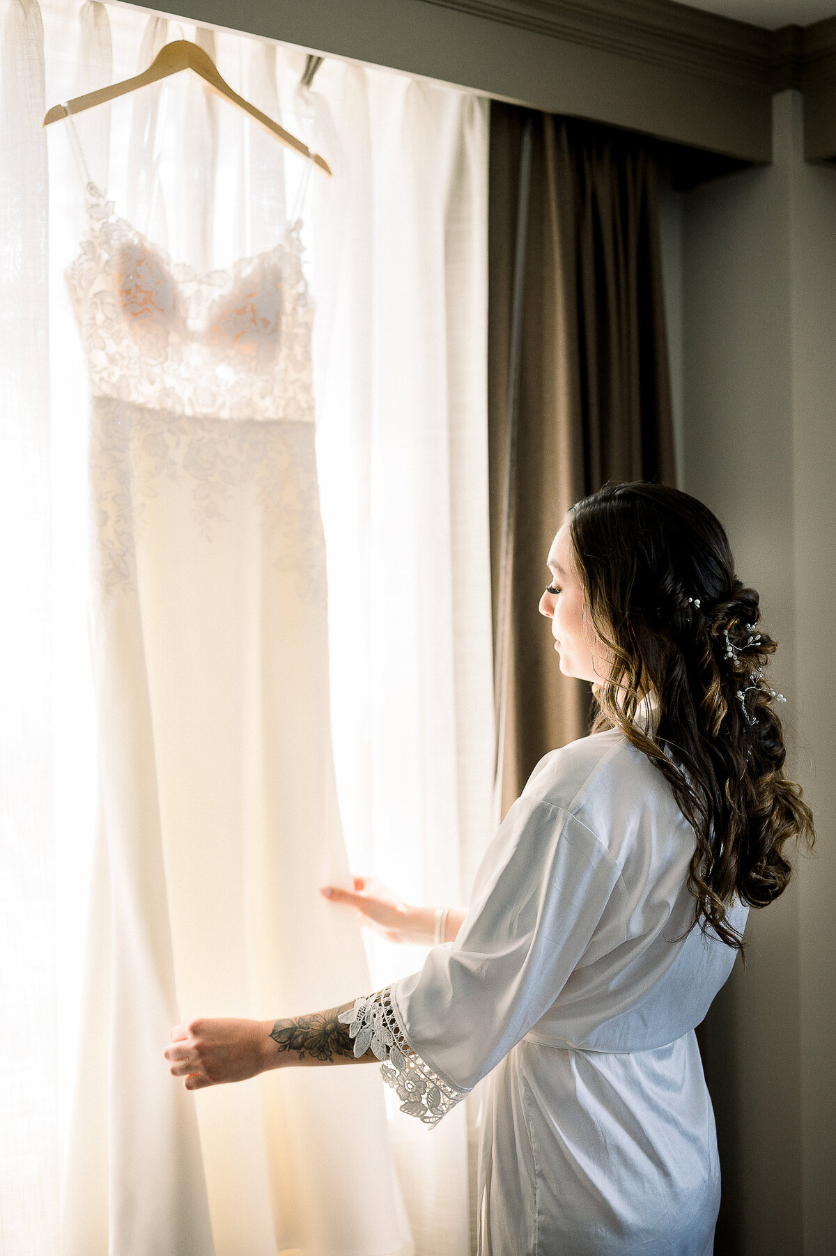 a bride looking at her wedding dress while wearing a robe