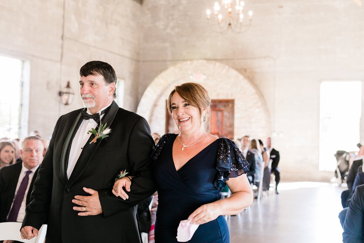 Groom's mom and father smiling at the groom was they walk down the aisle at Olde Dobbin Station.