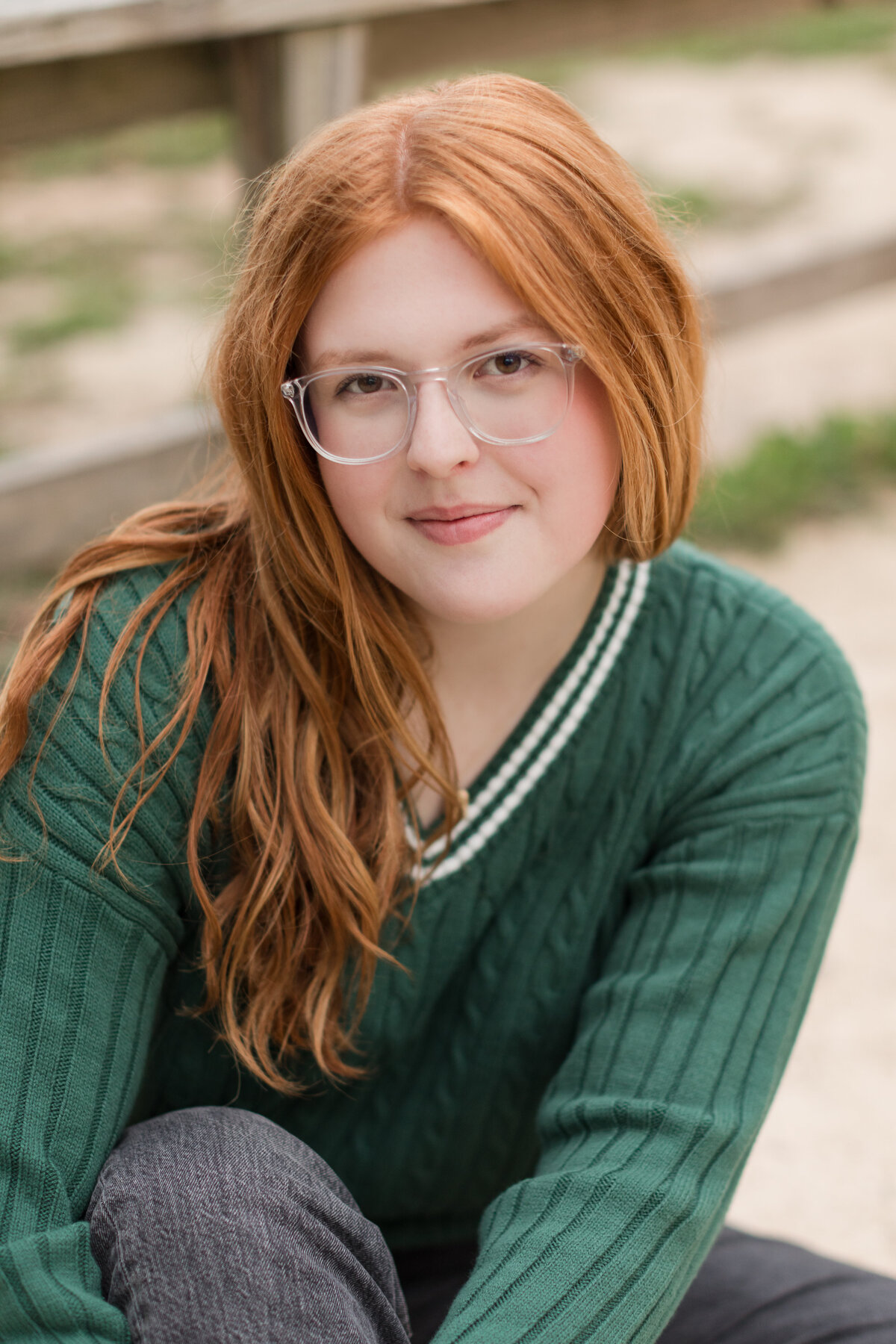 Senior girl seated on the ground smiling at the camera