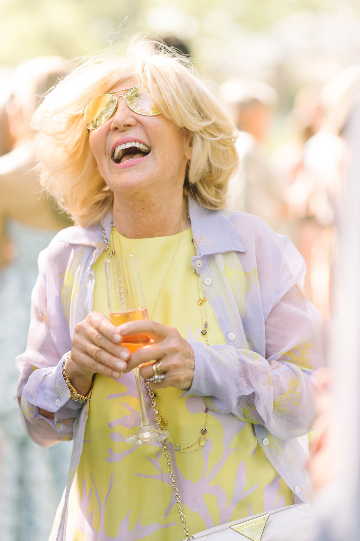 A woman in a vibrant brightly coloured outfit laughs during a wedding cocktail hour