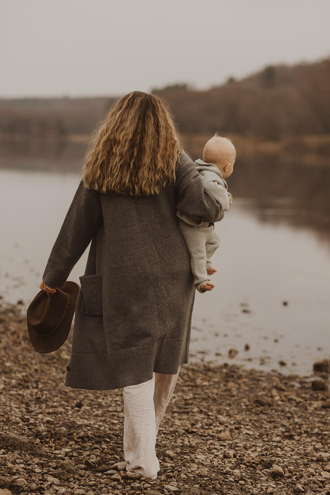 Photographer based in Minneapolis walks down the shoreline with her baby in tow