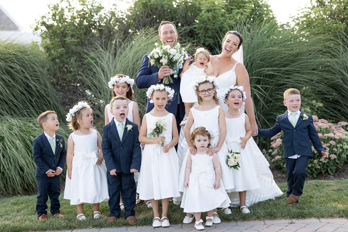 Bride and Groom pose with flower girls and ring bearers during wedding.