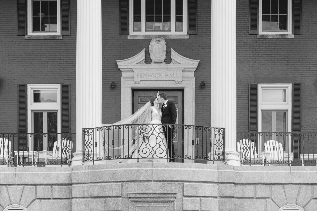 Blackj and white picture of a bride and groom kissing on a balcony