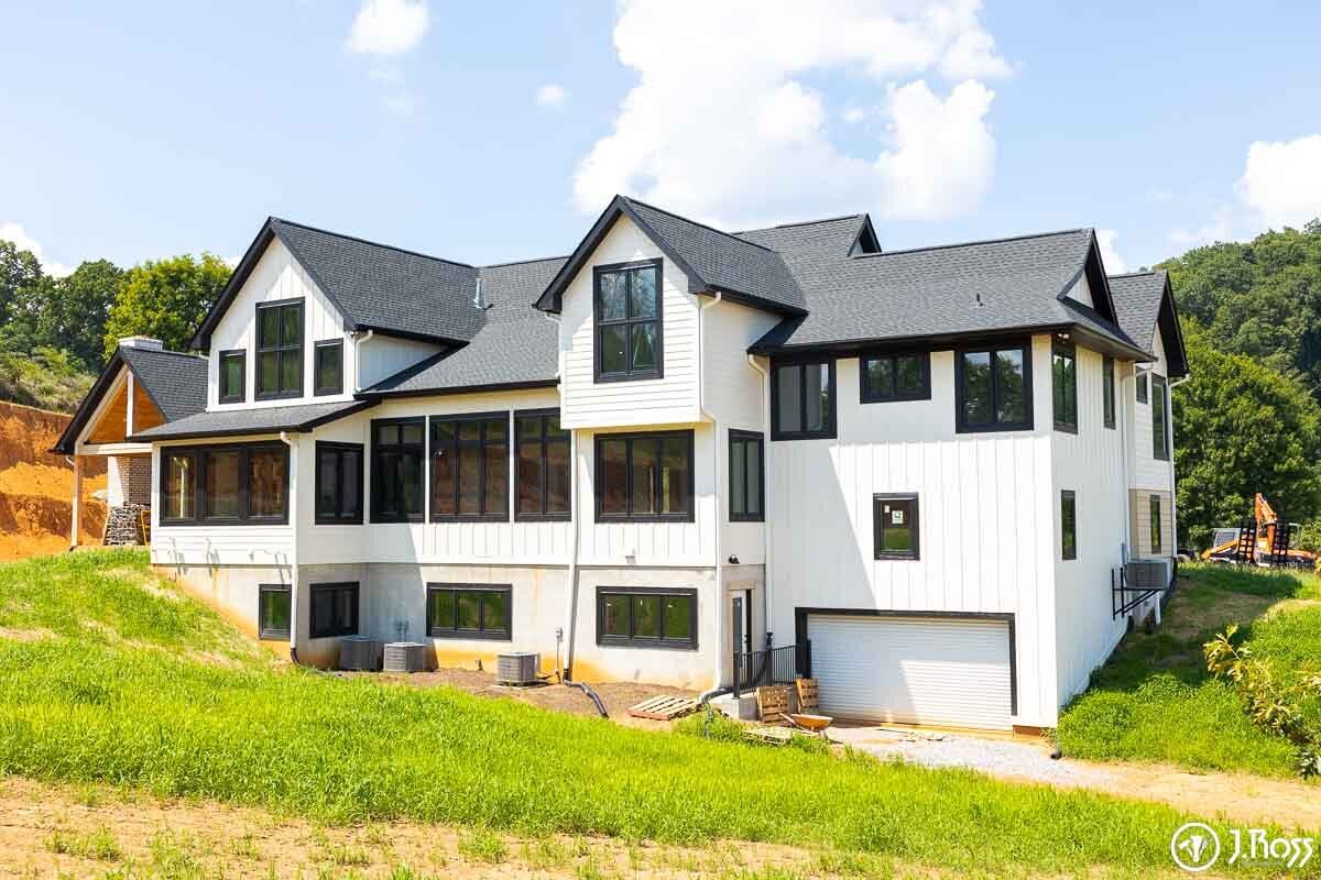 Back and side view of a white modern farmhouse with black-trimmed windows and basement-level garage door, emphasizing quality home outside painting, Kingsport, Tennessee.