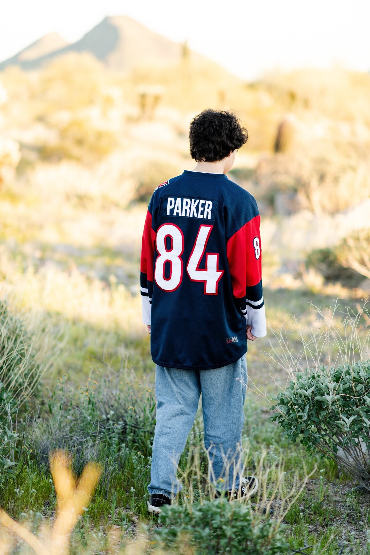 senior boy walking through the arizona desert in his pinnical high school hockey jesery