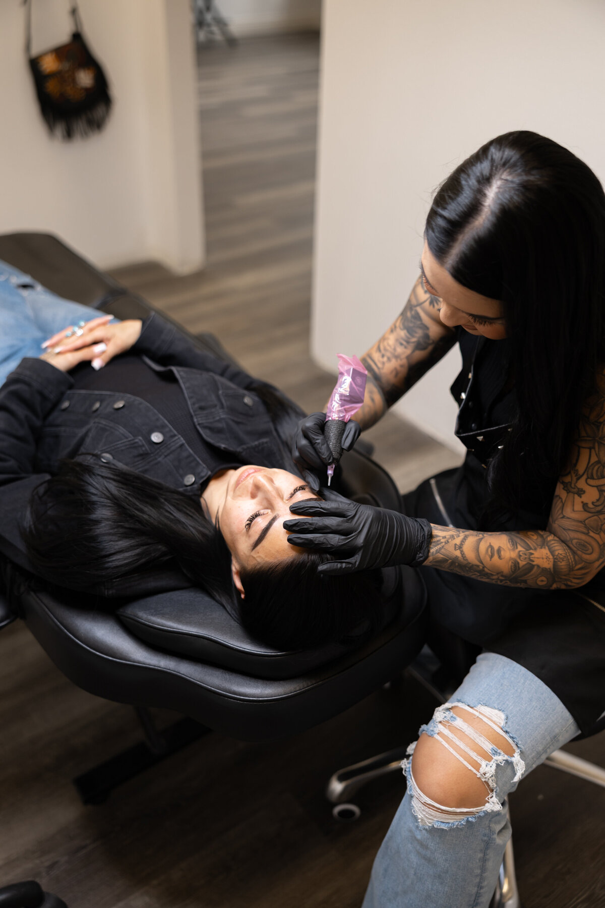 Makeup artist concentrating while performing detailed brow work under bright light. Photograph by Yucaipa branding photographer Kaitlyn Dawn Photography.