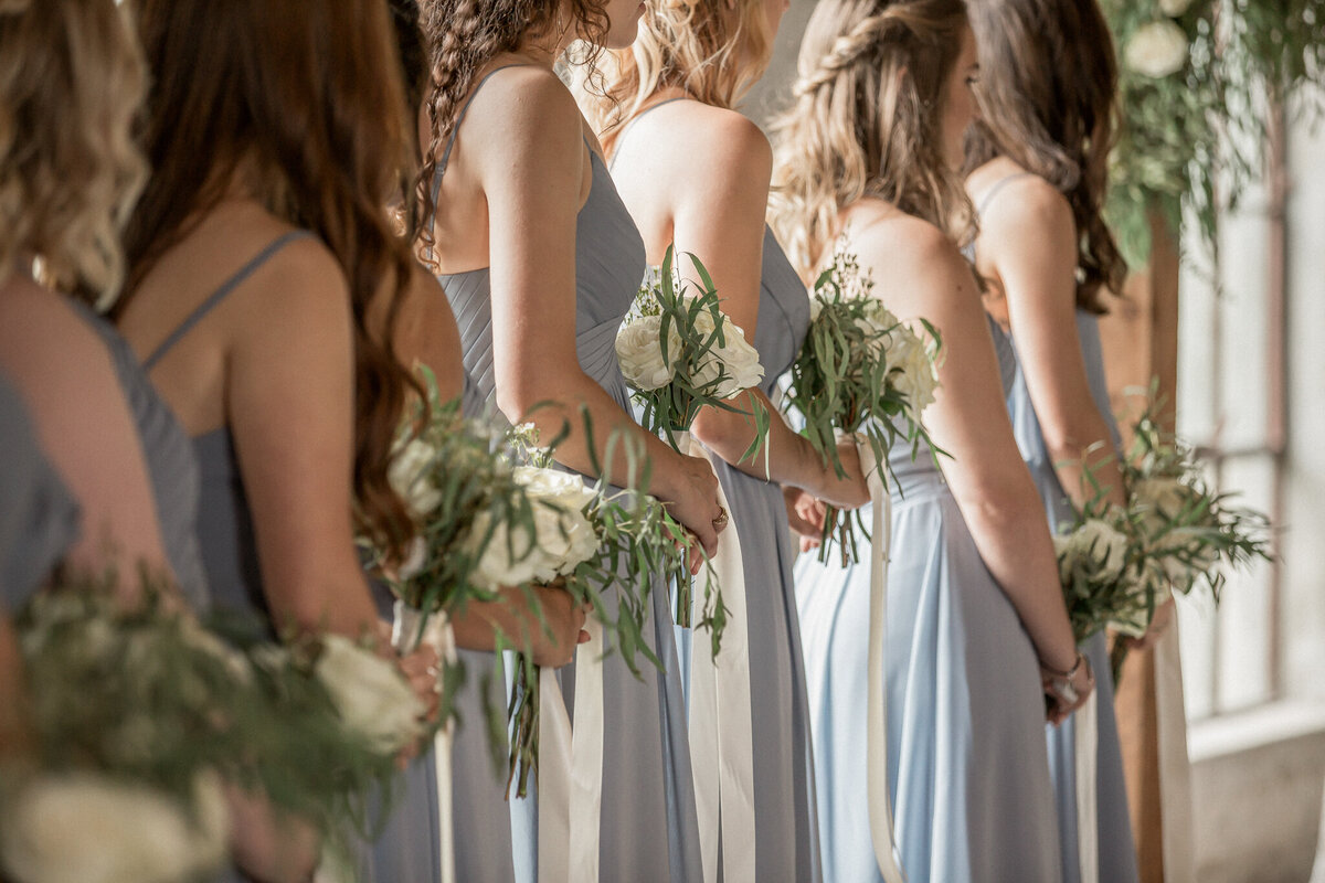 Close up of bridal party featuring their blue dresses and white bouquets