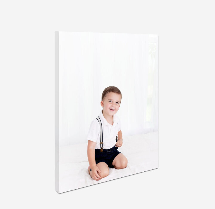 A canvas print of a toddler boy hangs on a wall