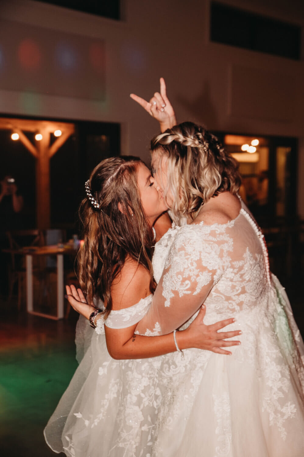 Brides kiss and show Rock On hand symbol as the night ends for their LGBTQ wedding