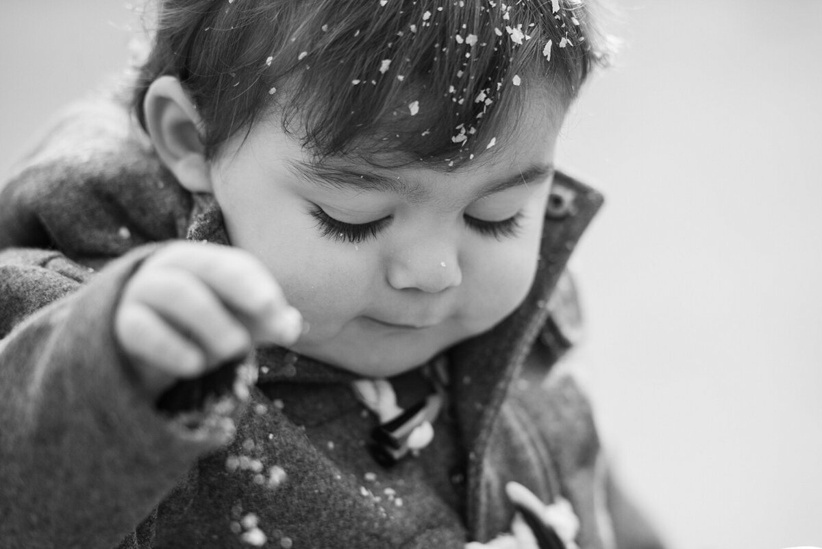 Closeup photo of a toddler boy with snowflakes in his hair