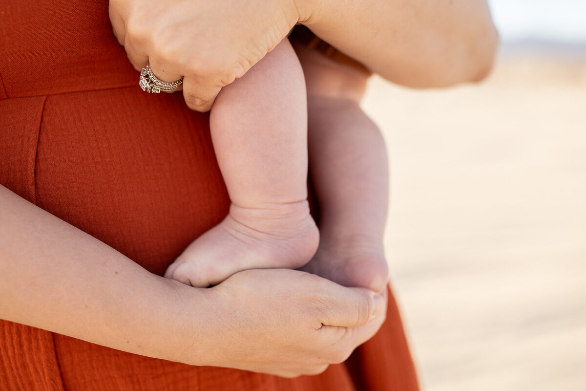 A mother holding her infant's foot in her hand. 