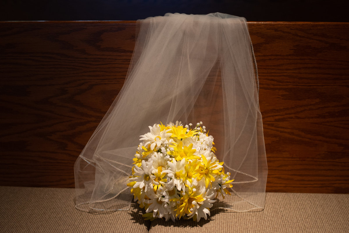 ambient light falls on daisies with veil on church pew