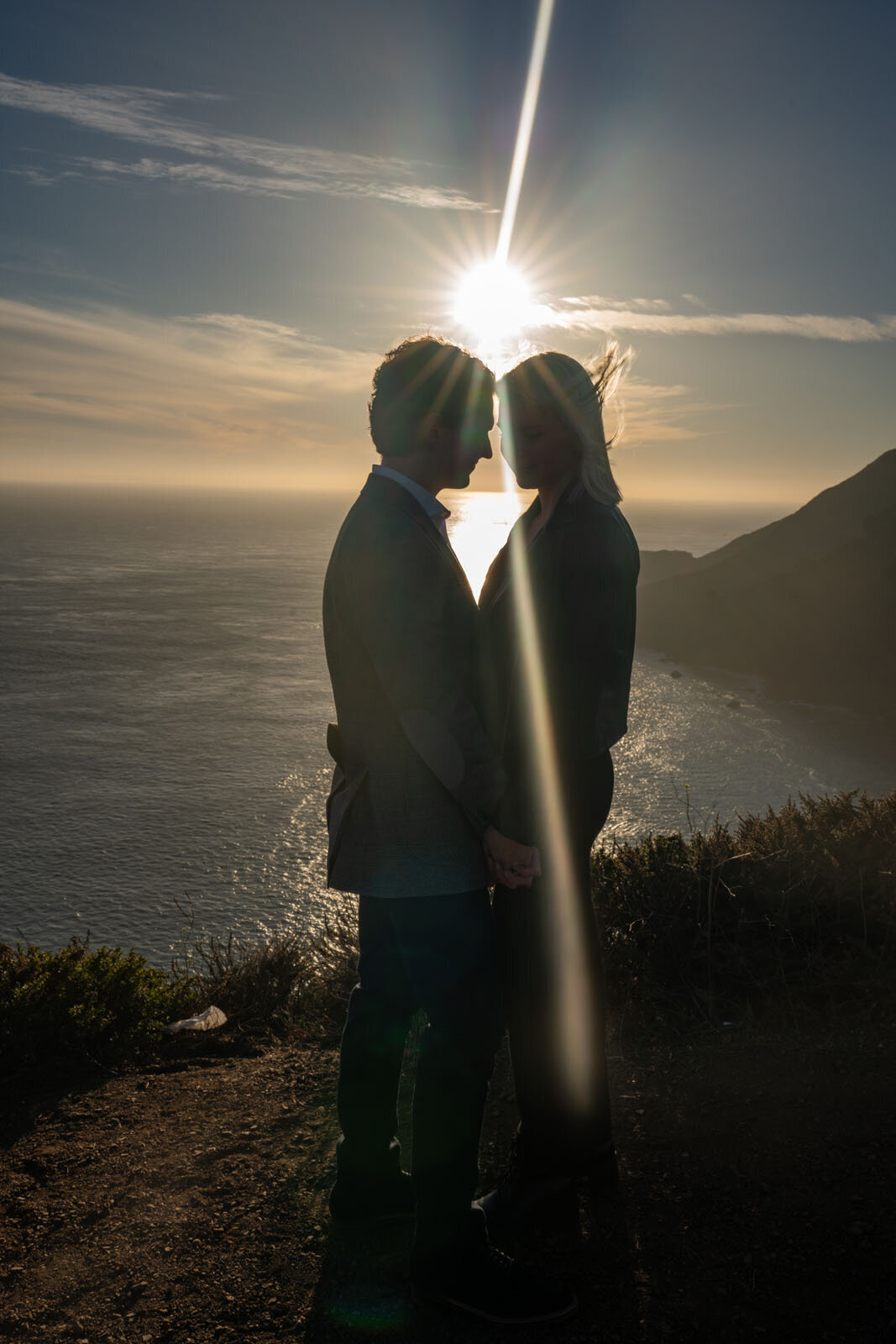 Couple embracing at sunset with the sunlight beaming between them as their foreheads touch each other