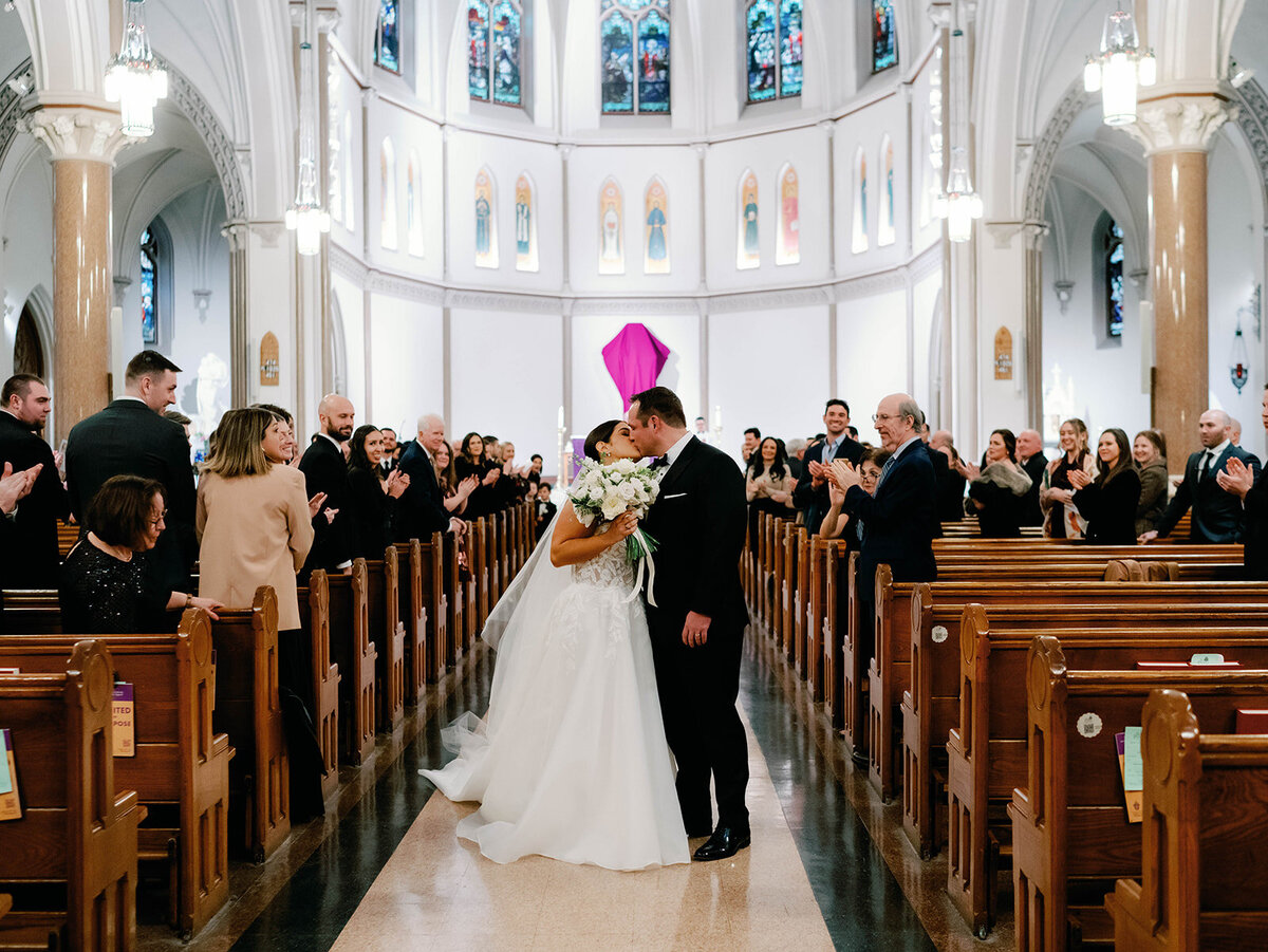 Bride and groom stop in the aisle for a kiss after the ceremony