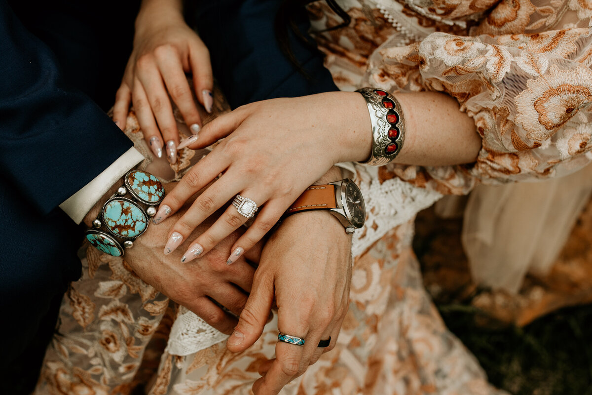 close up of bride and grooms hands together with southwest jewelry
