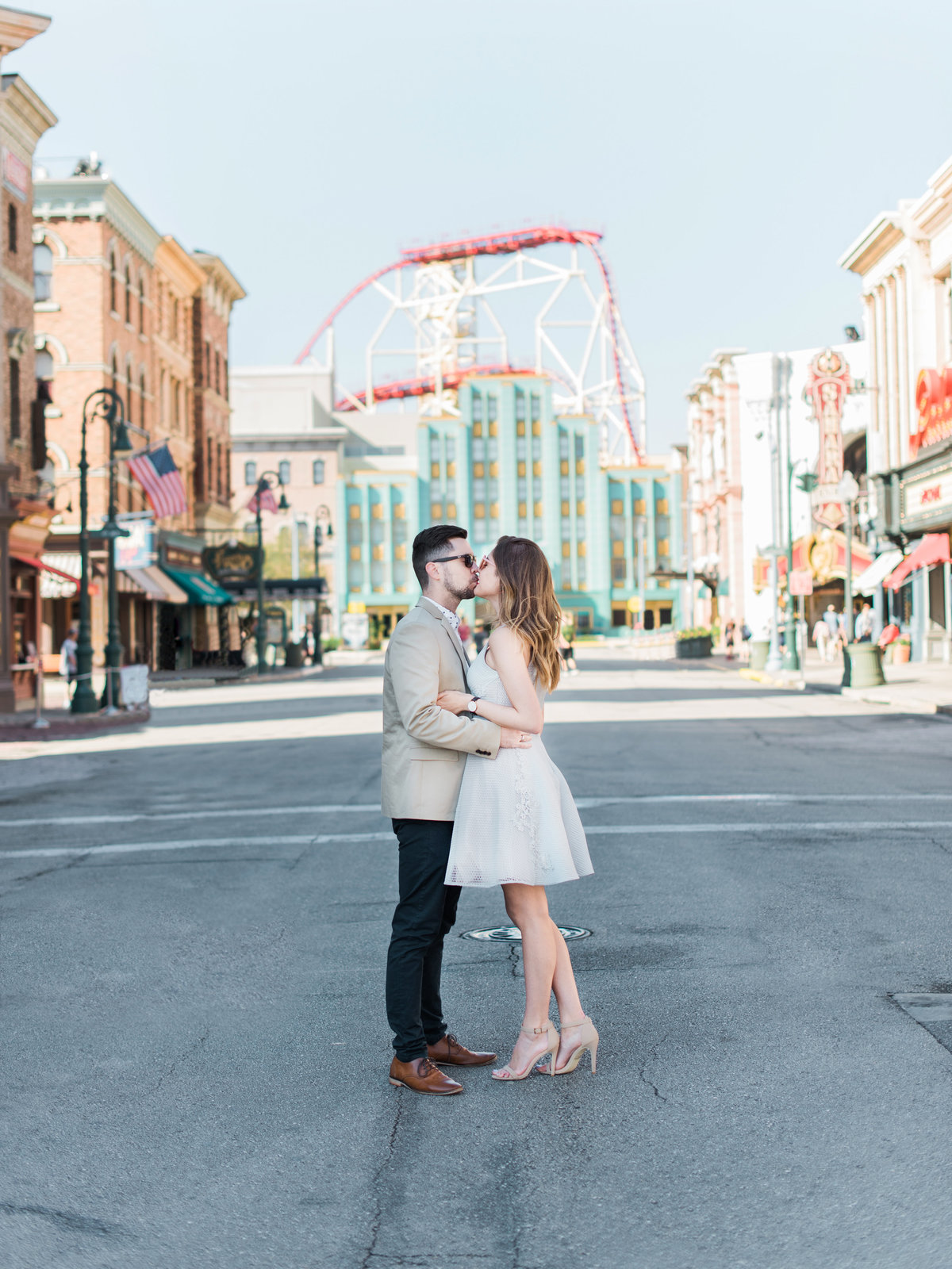 Couple kissing in Islands of Adventure during engagement session in front of roller coaster