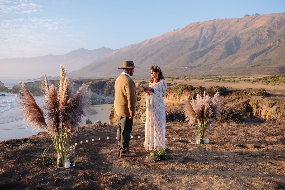 bride and groom stand on a cliffside and read vows during their northern california elopement