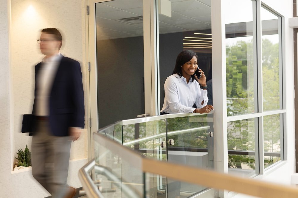 Glass hallway with a african-american woman talking on the phone and a blurred businessman walking past her