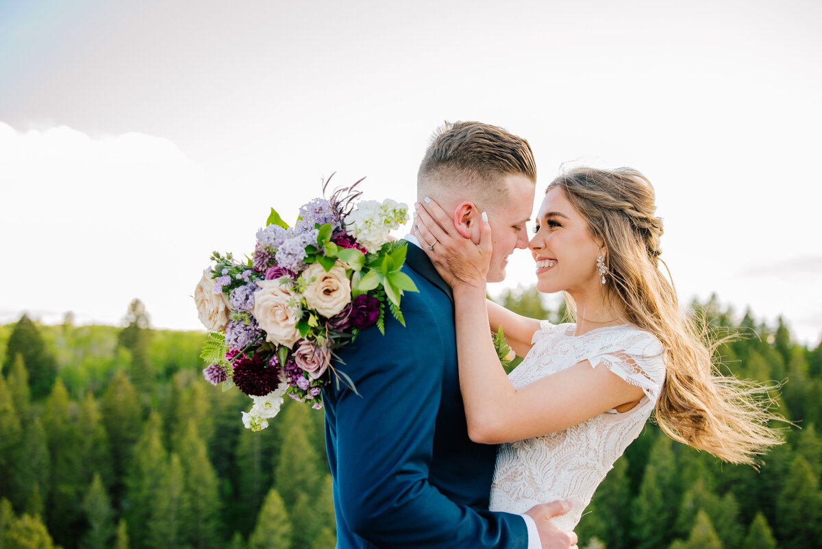 Jackson Hole photographers capture outdoor bridals with bride and groom hugging while bride holds bridal bouquet