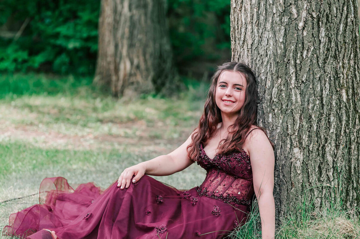 A young girl sitting against a tree
