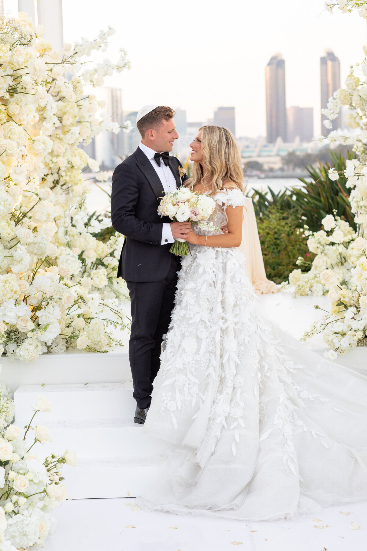 A bride and groom hugging and smiling at each other