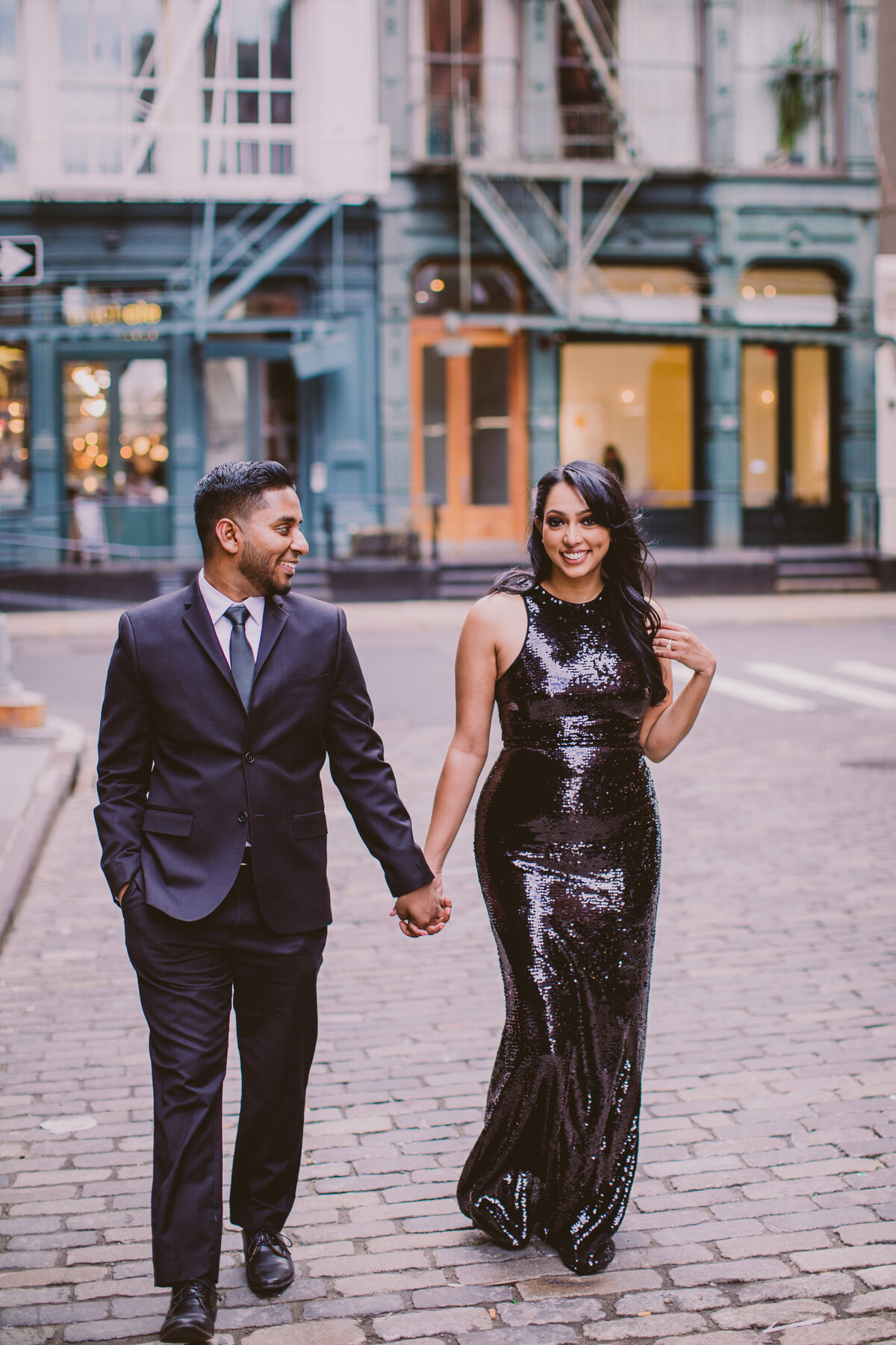 A couple during their engagement shoot walking down the cobblestone street in soho, nyc