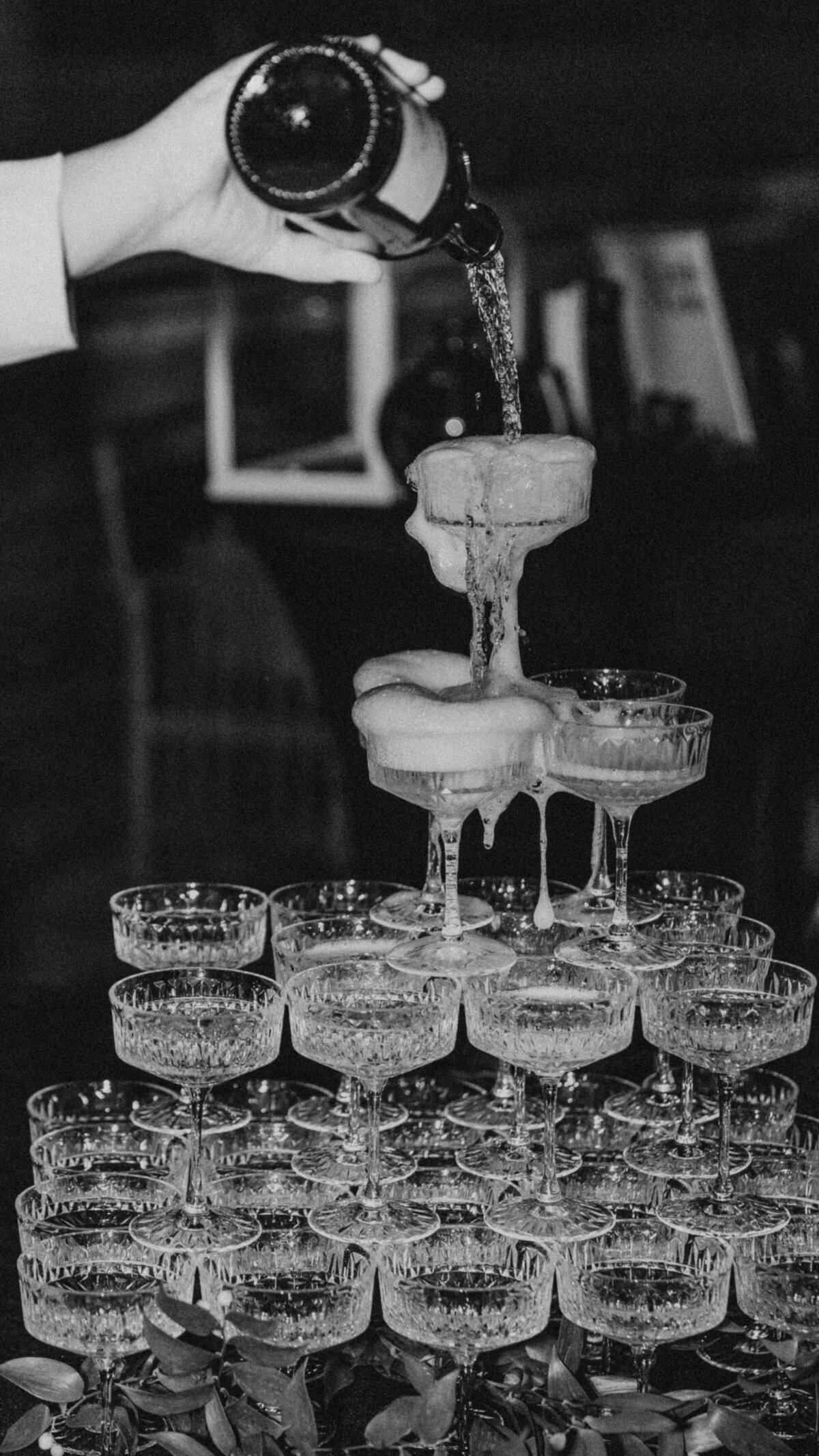 Black and white image of a champagne tower with bubbles cascading down glasses