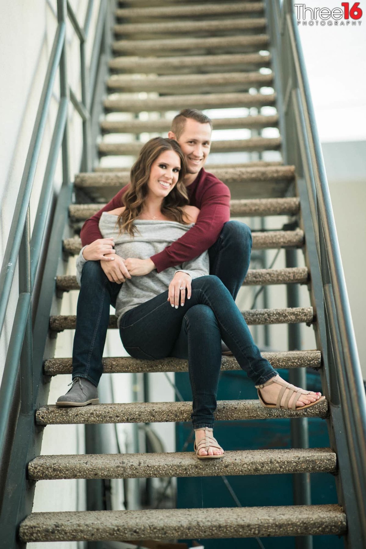 Engaged couple cozy up on a outdoor staircase