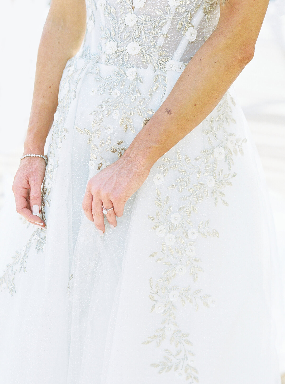 A close-up of a bride’s sparkling embellished wedding gown with intricate floral embroidery, perfect inspiration for modern bridal fashion.