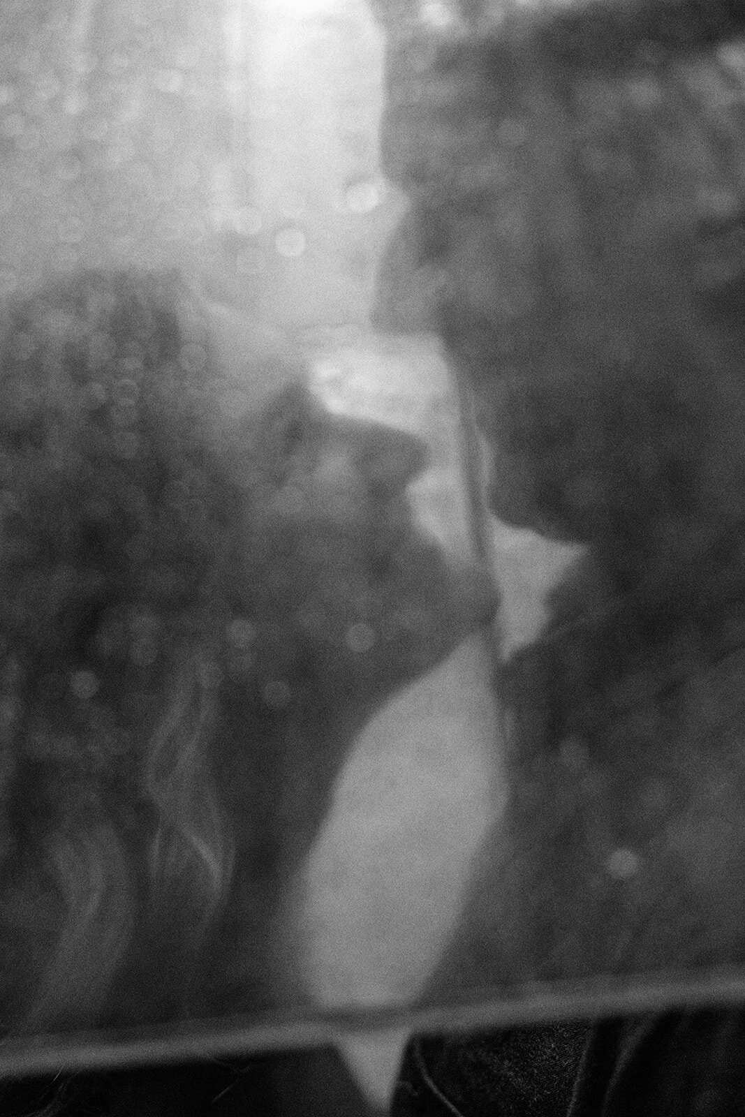 Up close image of a couple's face underneath a clear umbrella. 