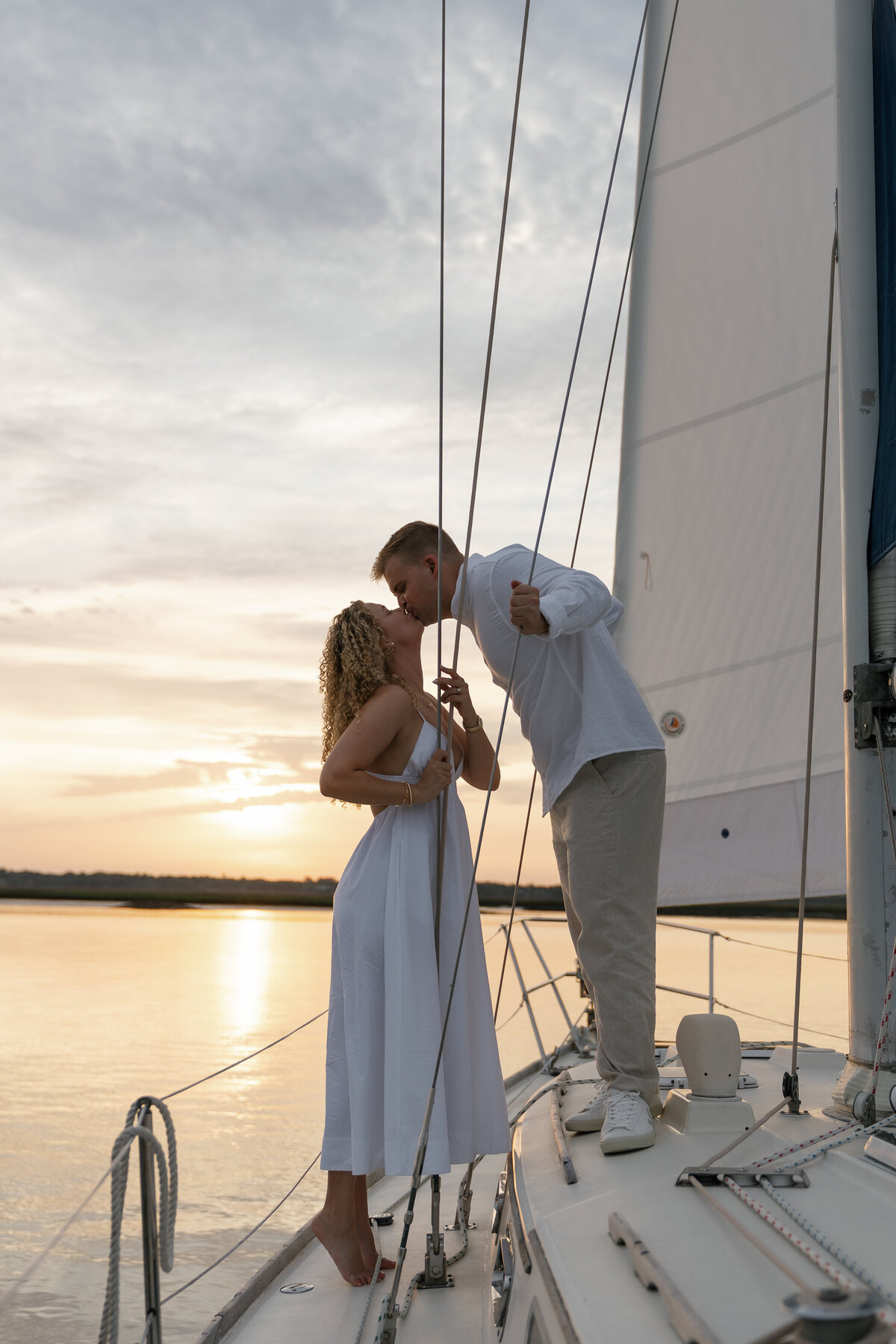 Couple kissing on a sailboat at sunset taken by Shelby Ann Photos, florida engagement photographer