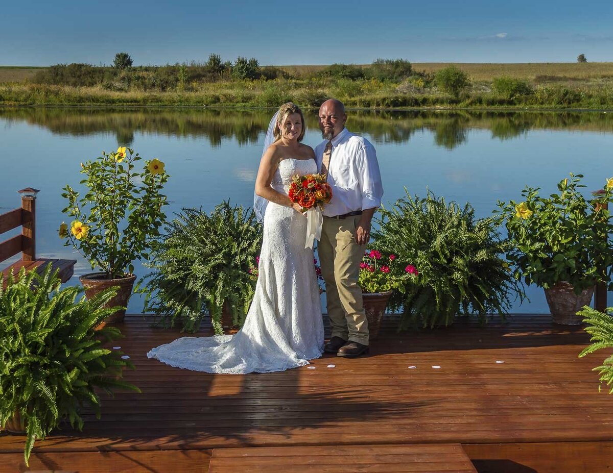 Newlyweds pose in front of a beautiful lake for their wedding photos.