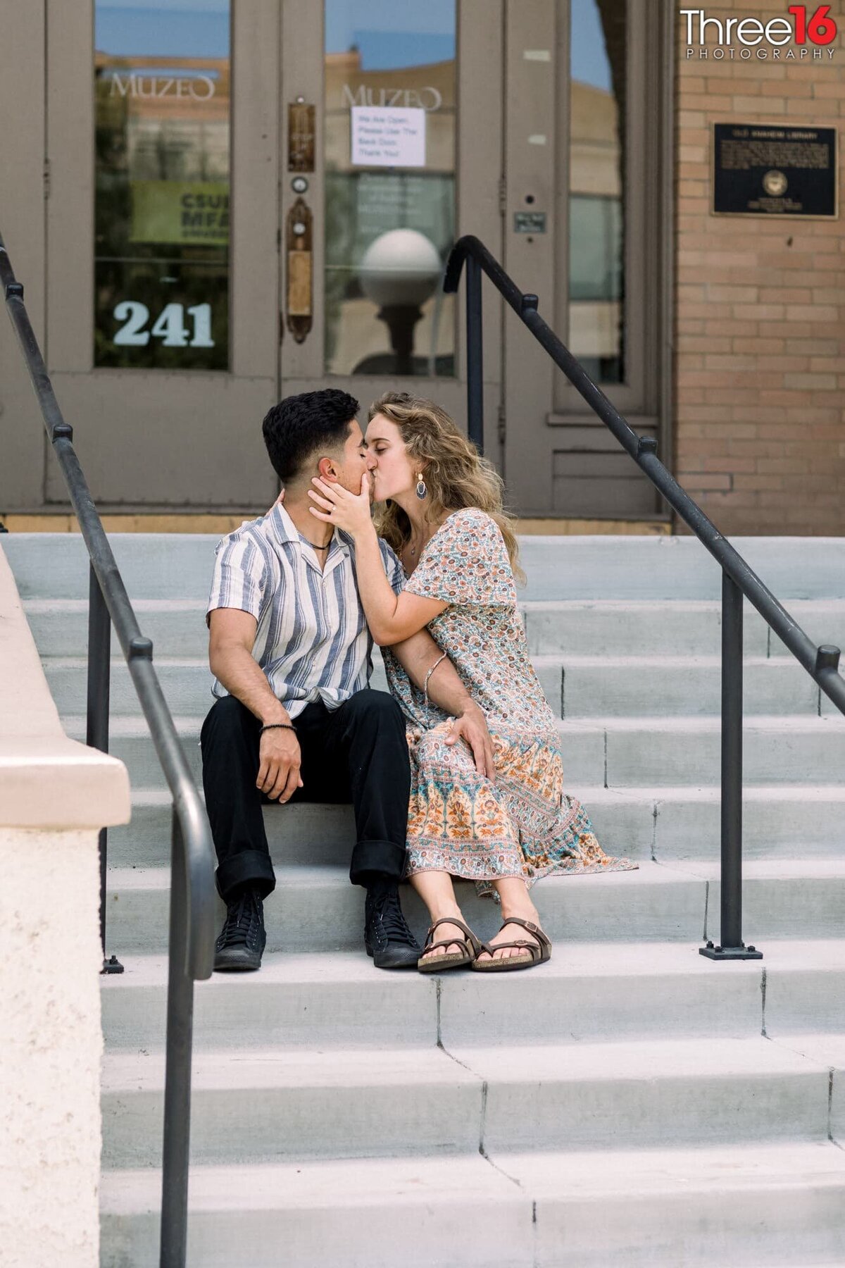 Romantic kiss while sitting on the Anaheim Library steps during engagement photo shoot