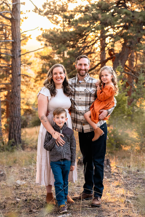 A family of four poses and smiles for their family photos.