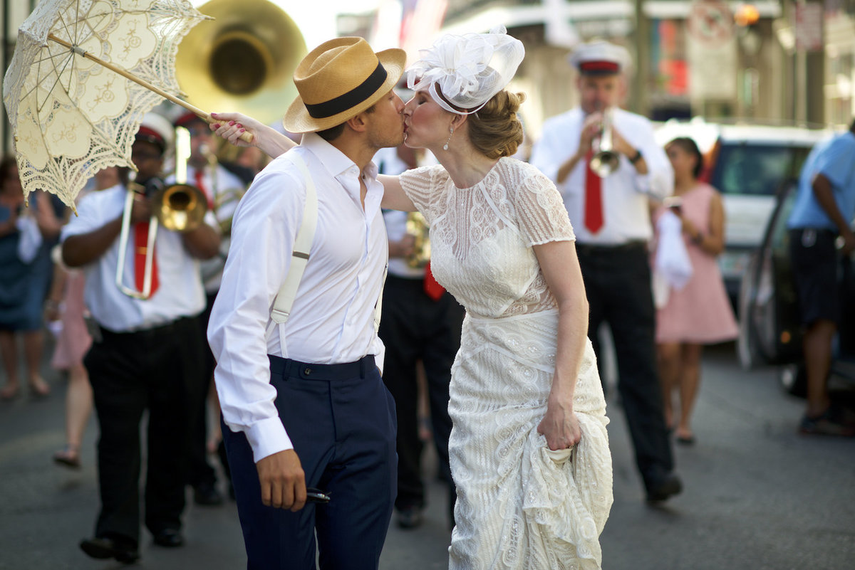 a wedding couple kisses during a second line parade at their wedding in New Orleans