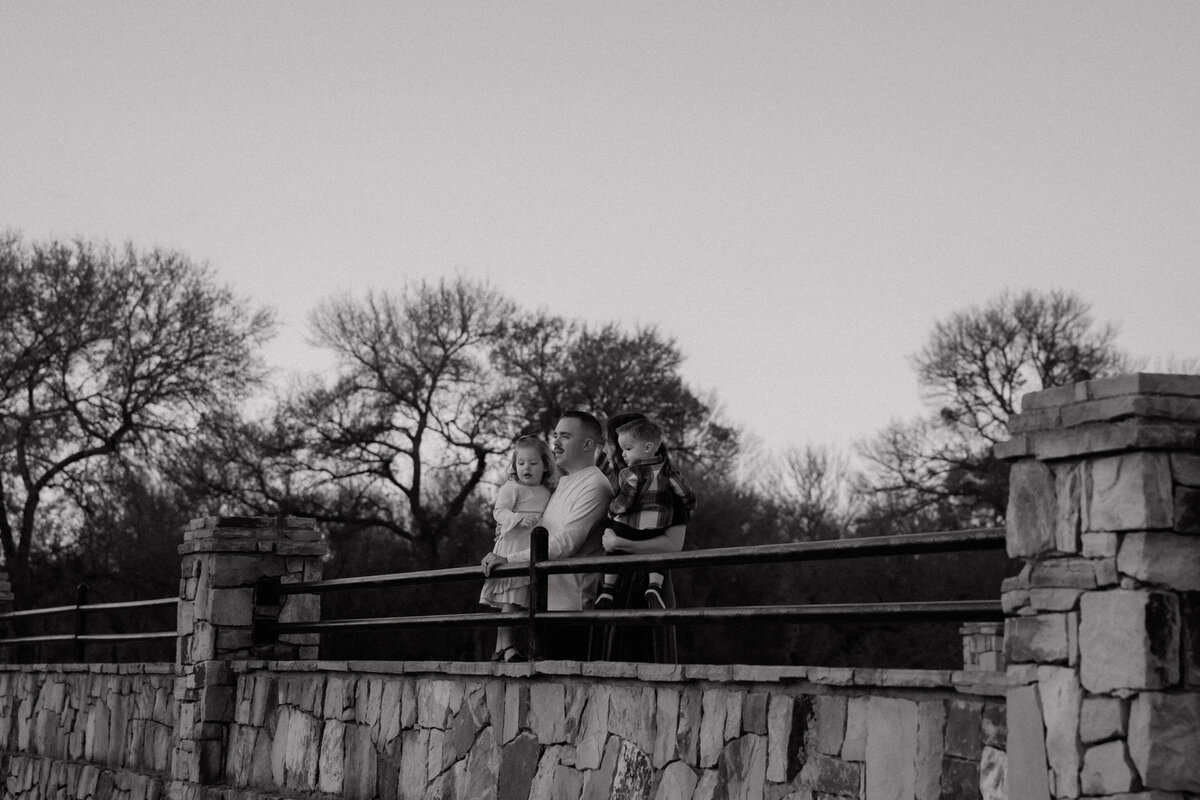 family on bridge looking over water