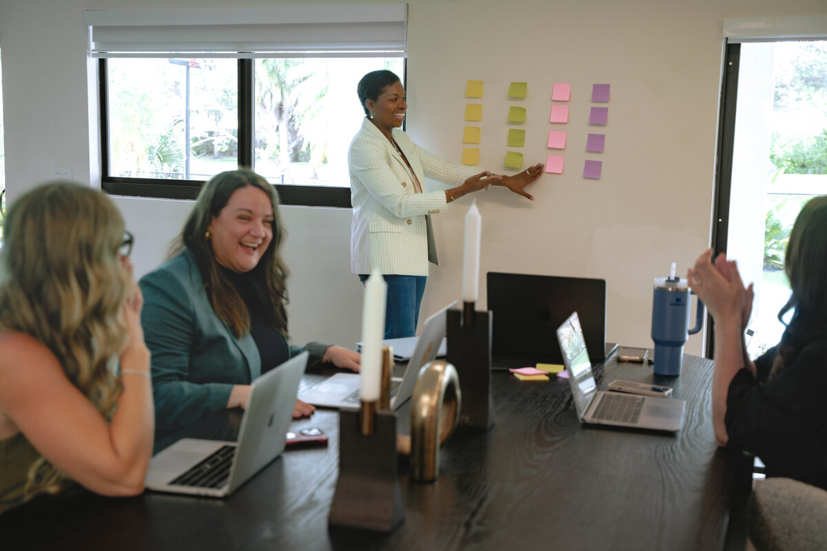 Black career coach for women coaching round table with post its on wall