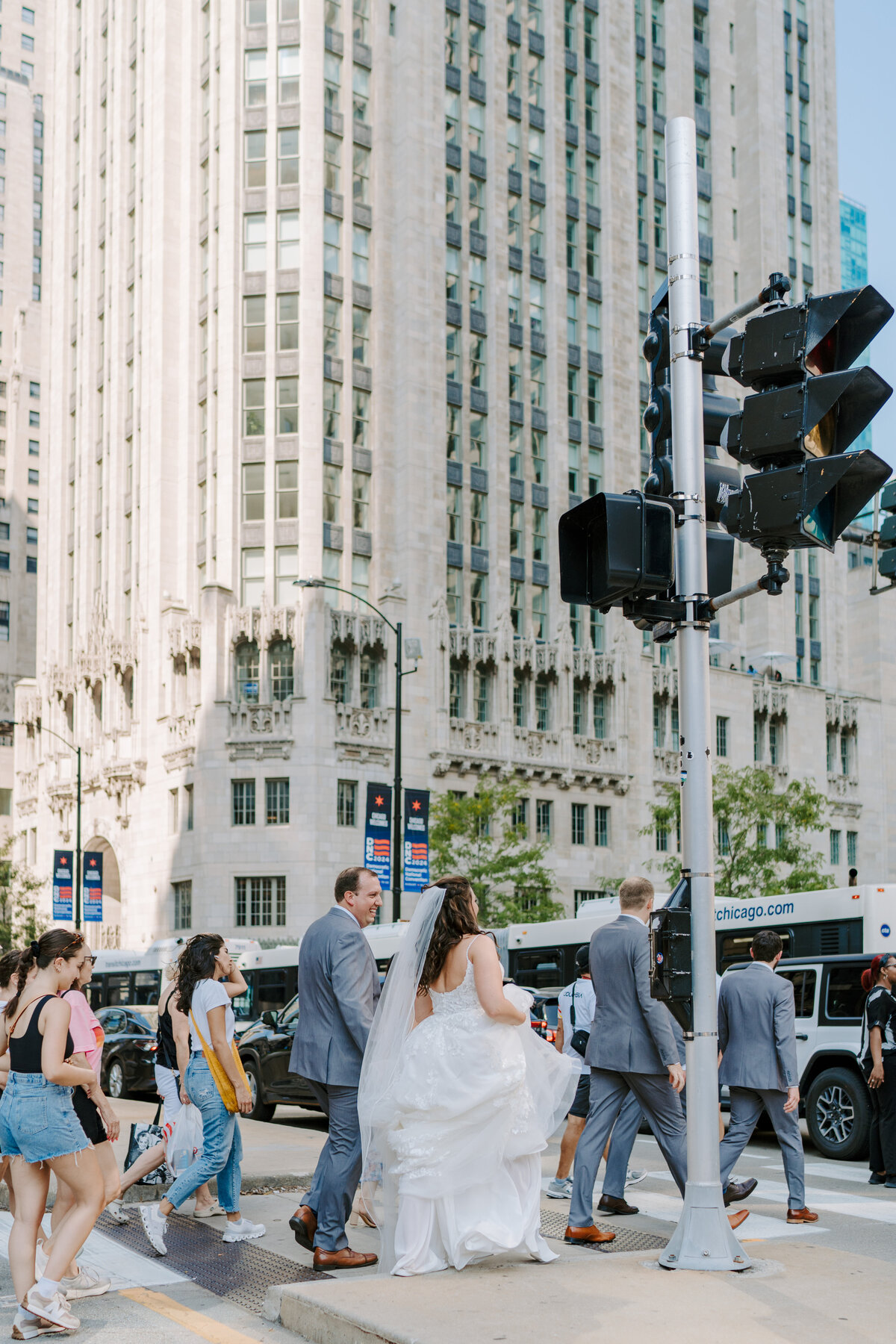 A couple is walking through a busy crosswalk after their wedding portraits in downtown Chicago. 