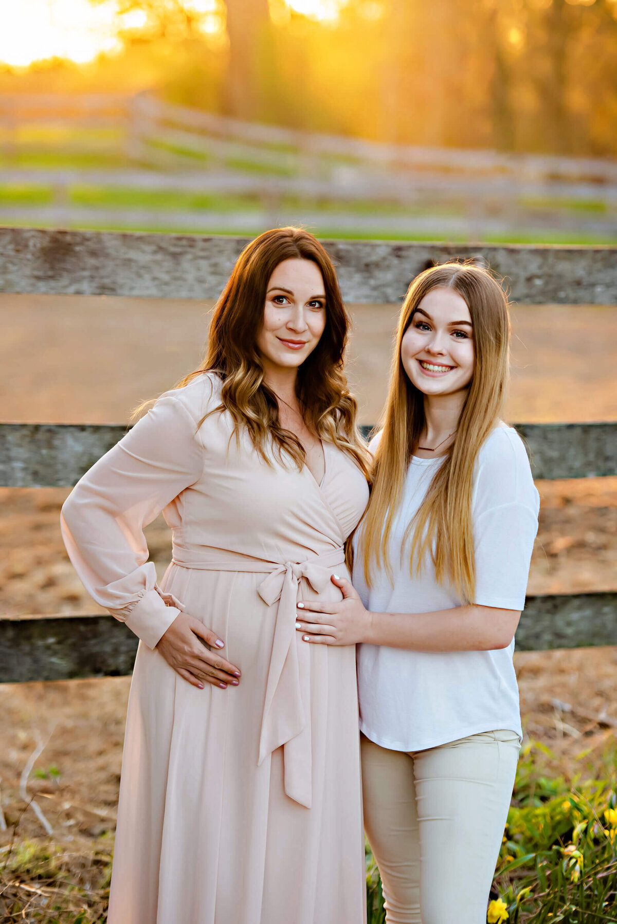 Pregnant woman standing with teenage daughter on a Toronto farm for their maternity photos.