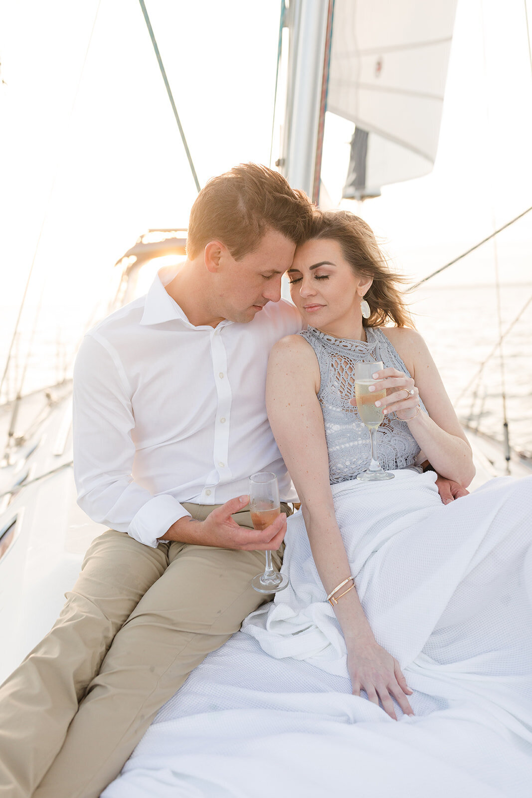 Engagement photos of couple embracing on a sailboat with champagne
