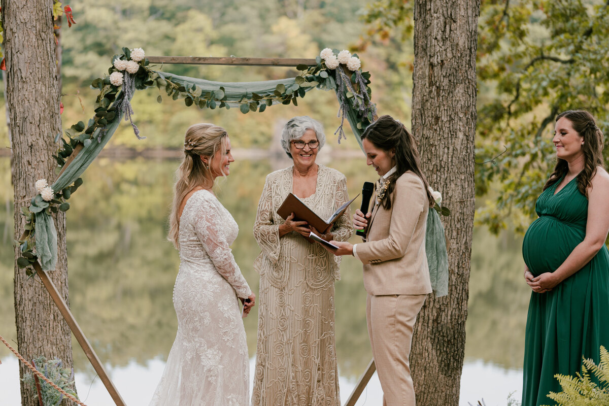 Newlyweds standing during their wedding ceremony as one says their vows into a microphone 