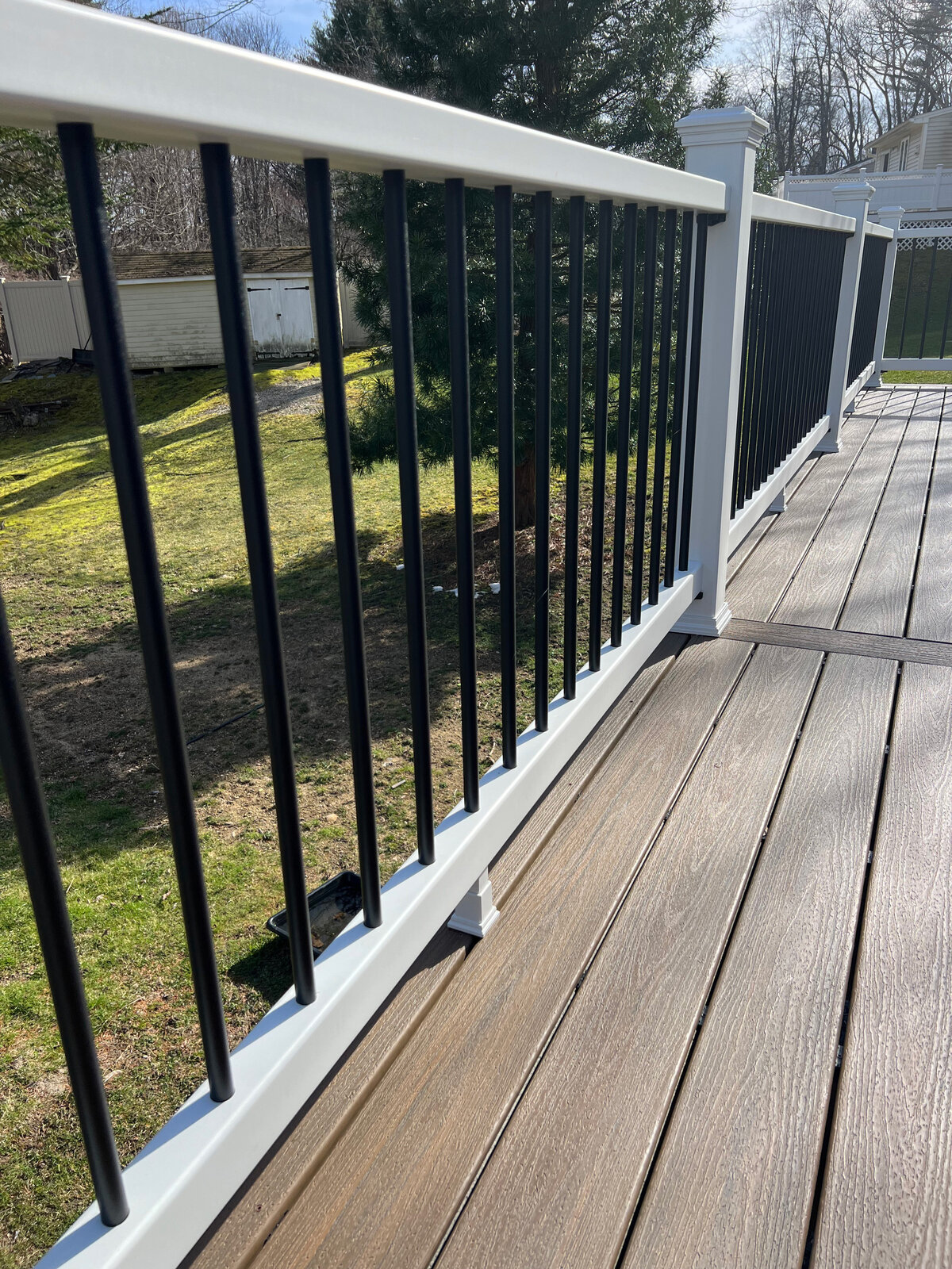 A natural brown composite deck wit grain with white and black PVC railings