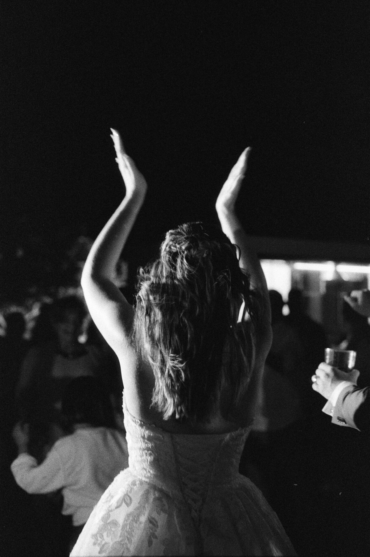 Destination Wedding in Spain | black and white film image of bride clapping above her head on the dance floor of her wedding reception