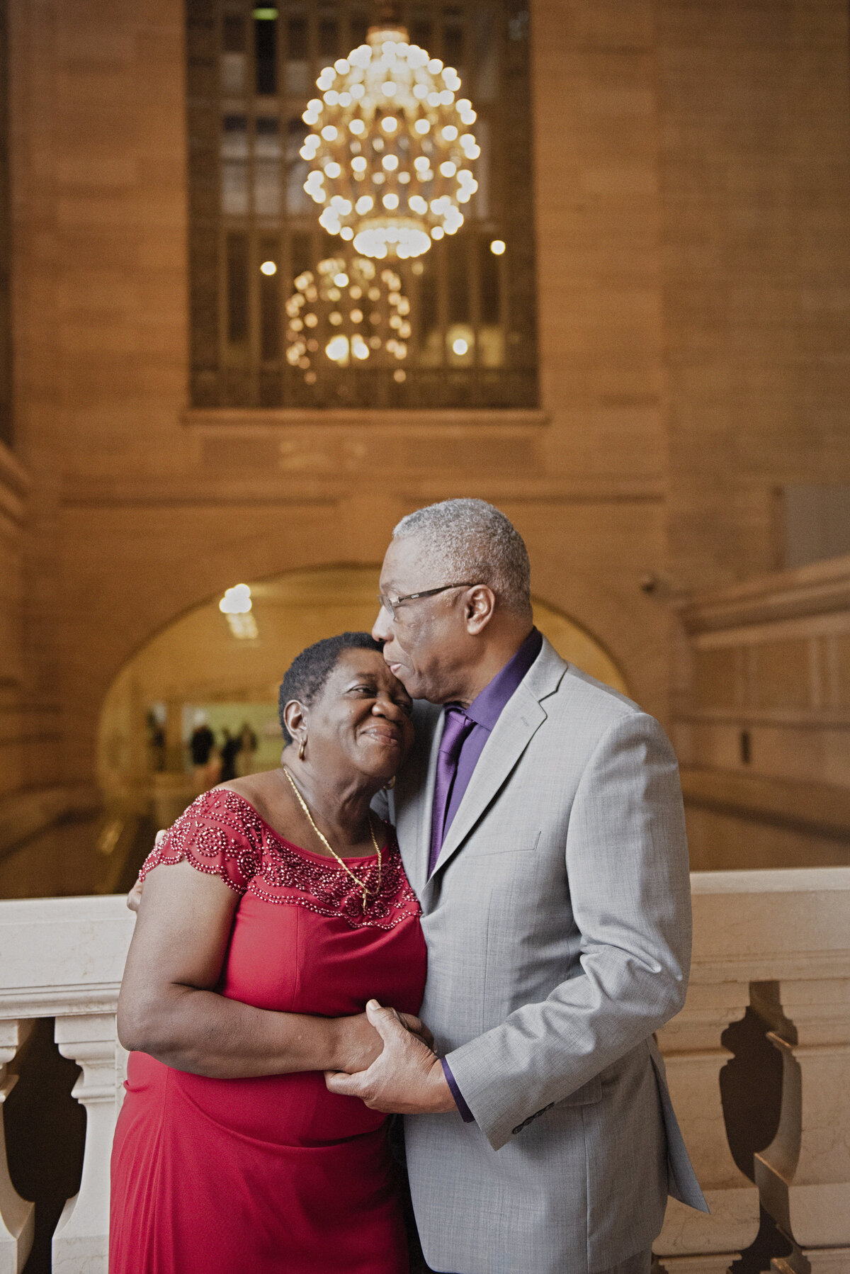 A person kissing their partner's head in a train station