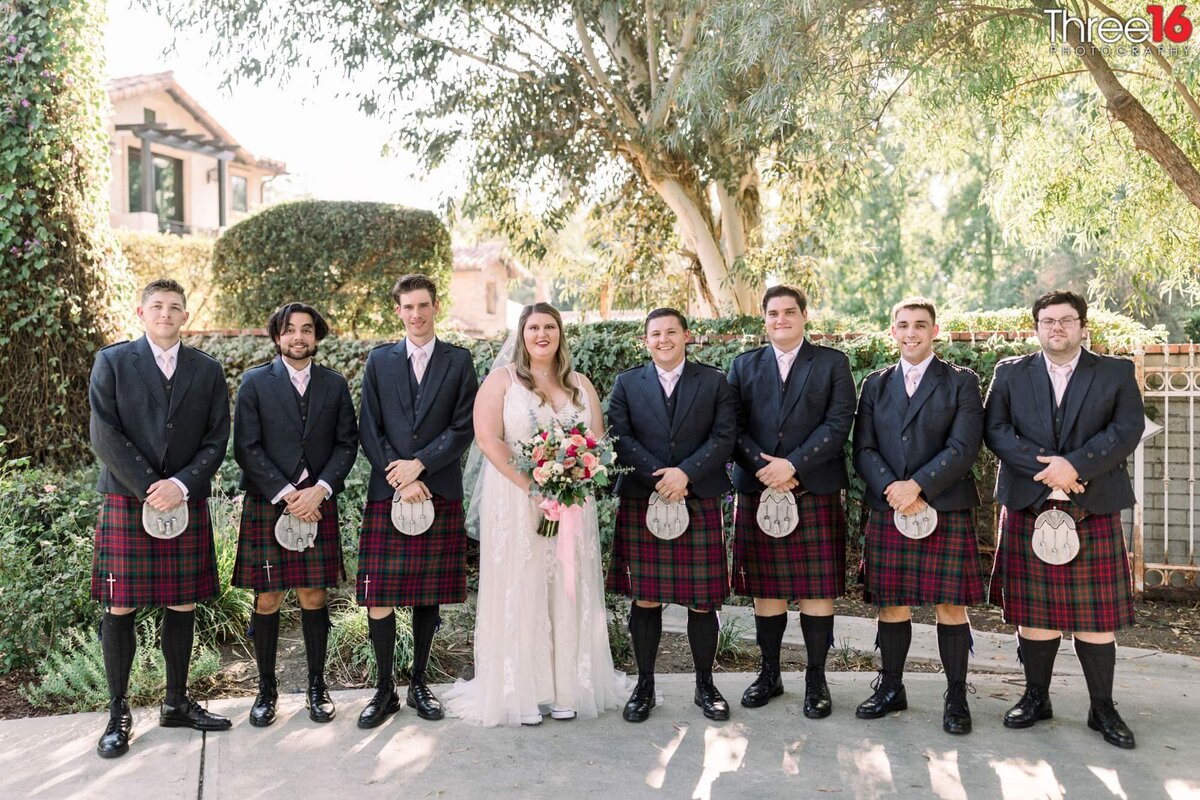Bride and Groom pose with the Groomsmen that are wearing kilts