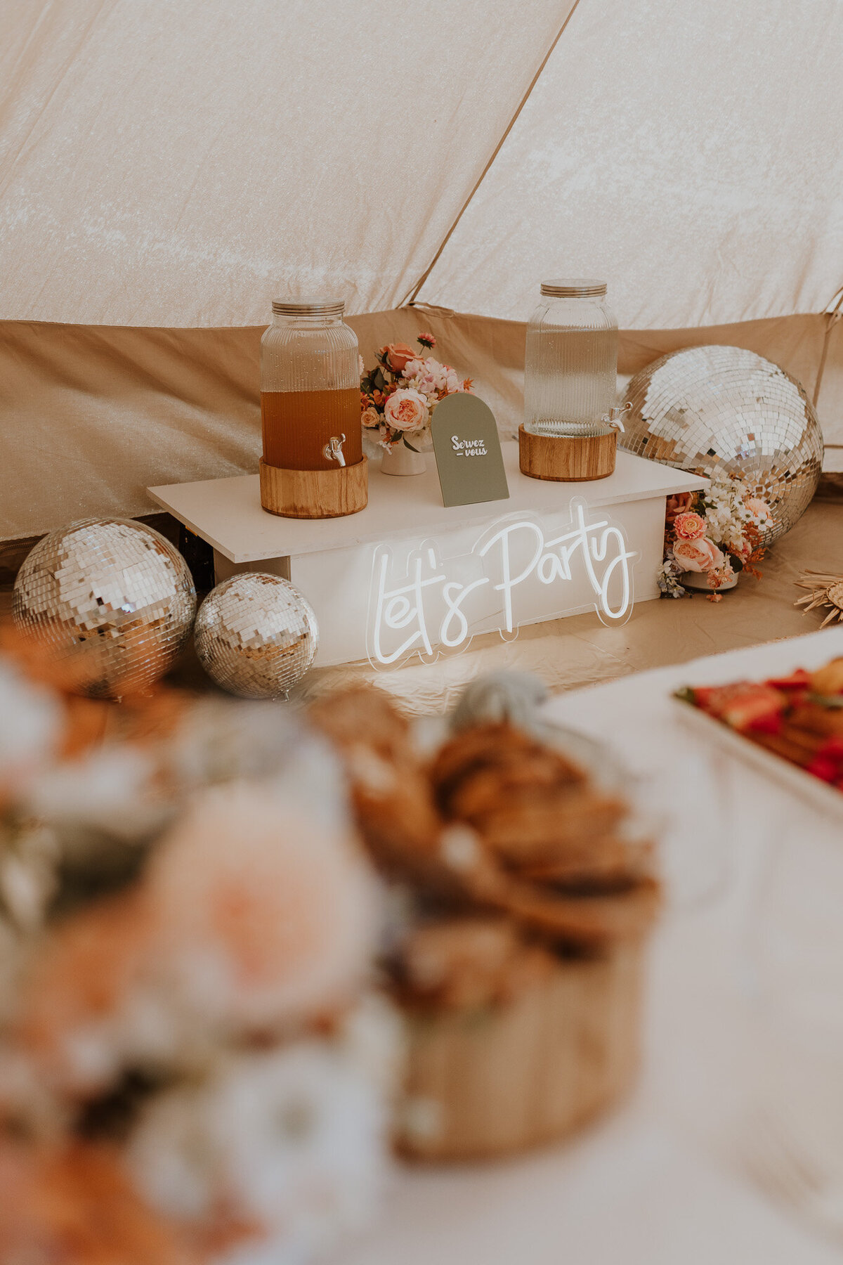 Photo d'un décor d'EVJF : table de buffet décoré de fleurs pastel et boules disco.