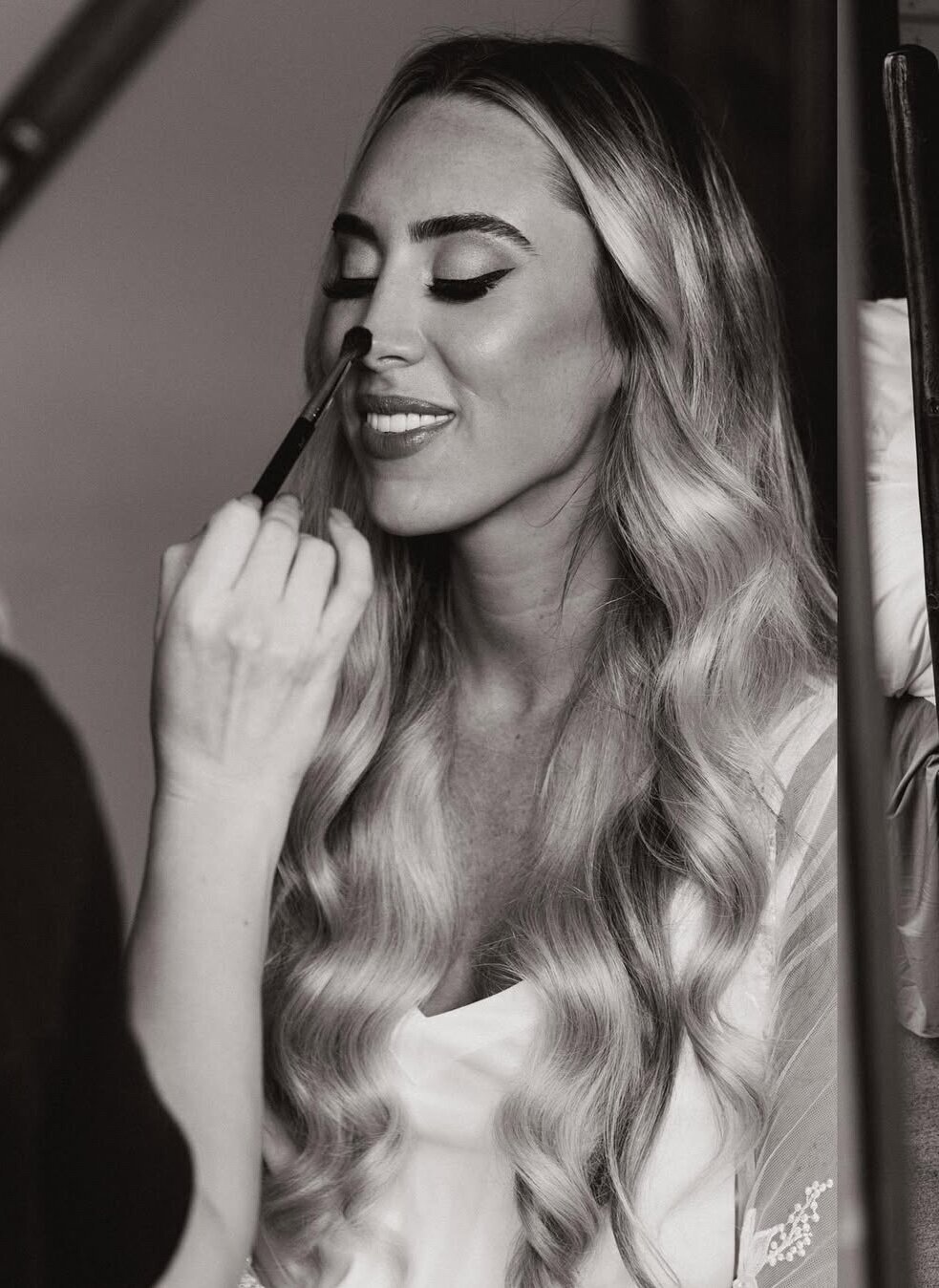 Park City, Utah hair and makeup artist brushes a bride's nose as a finishing touch to her bridal beauty look